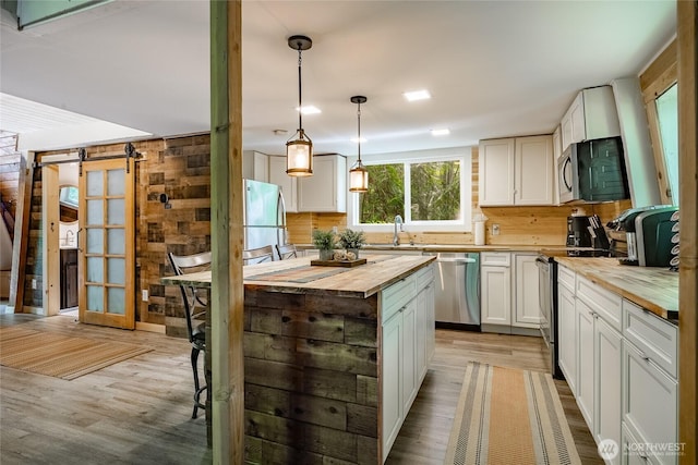 14001 Welcome Rd, Glacier, WA 98244 - kitchen featuring wood counters, stainless steel appliances, light wood-type flooring, wooden walls, and decorative light fixtures