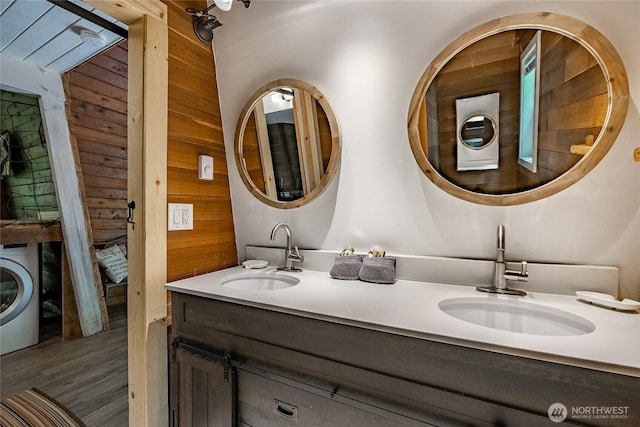 14001 Welcome Rd, Glacier, WA 98244 - bathroom featuring washer / clothes dryer, wooden walls, double vanity, and wood finished floors