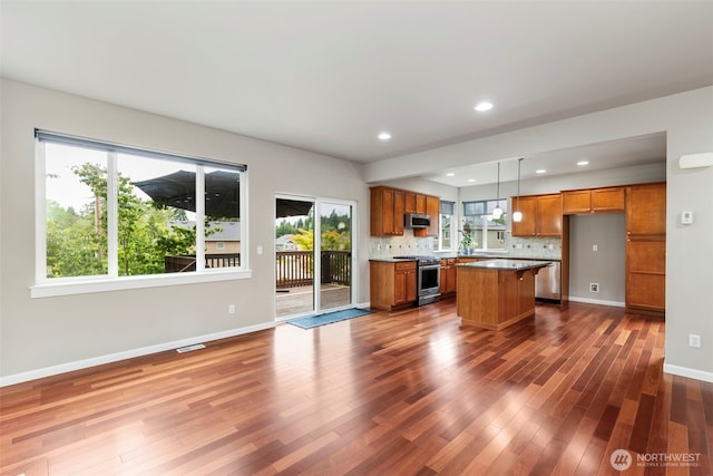 6372 Juanita Cir NE, Bremerton, WA 98311 - kitchen with stainless steel appliances, brown cabinetry, dark wood finished floors, decorative backsplash, and decorative light fixtures