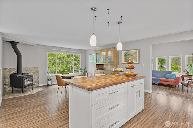 17225 429th Ave SE, North Bend, WA 98045 - kitchen featuring butcher block counters, open floor plan, light wood-style floors, a wood stove, and glass insert cabinets