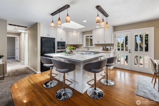 14715 57th Ave S, Tukwila, WA 98168 - kitchen featuring black appliances, white cabinetry, light countertops, a kitchen breakfast bar, and pendant lighting