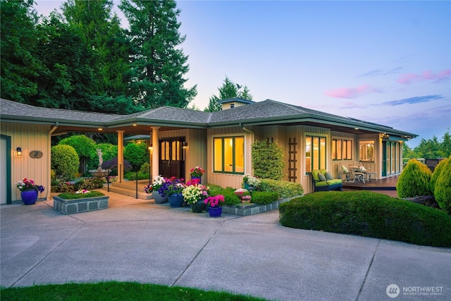 7001 Palm Ln, Anacortes, WA 98221 - back of house at dusk featuring concrete driveway, a porch, and a shingled roof