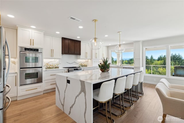 7001 Palm Ln, Anacortes, WA 98221 - kitchen featuring appliances with stainless steel finishes, a center island, light wood-style floors, recessed lighting, and white cabinetry