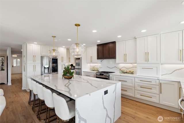 7001 Palm Ln, Anacortes, WA 98221 - kitchen featuring appliances with stainless steel finishes, white cabinetry, light stone countertops, light wood-type flooring, and recessed lighting