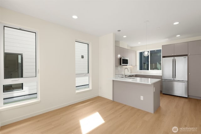 9217B 14th Ave NW, Seattle, WA 98117 - kitchen with appliances with stainless steel finishes, gray cabinets, light wood finished floors, a peninsula, and decorative light fixtures