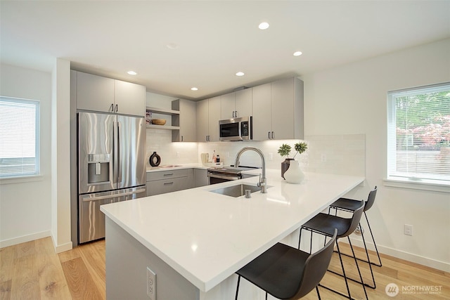 2904 W Bertona St, Seattle, WA 98199 - kitchen featuring stainless steel appliances, open shelves, a peninsula, a breakfast bar area, and decorative backsplash