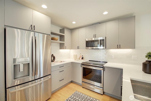 2904 W Bertona St, Seattle, WA 98199 - kitchen with appliances with stainless steel finishes, open shelves, light countertops, light wood-style flooring, and decorative backsplash