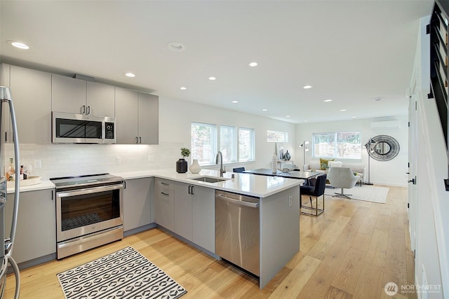 2904 W Bertona St, Seattle, WA 98199 - kitchen with gray cabinets, appliances with stainless steel finishes, a wall mounted AC, a peninsula, and light wood-type flooring