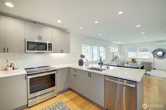 2904 W Bertona St, Seattle, WA 98199 - kitchen featuring appliances with stainless steel finishes, gray cabinets, a peninsula, light wood finished floors, and recessed lighting