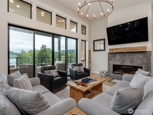 168 Lakeside Dr, Mossyrock, WA 98564 - living area featuring healthy amount of natural light, a chandelier, a high ceiling, a glass covered fireplace, and wood finished floors
