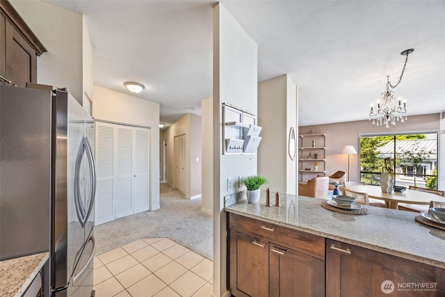 2360 43rd Ave E Unit 404, Seattle, WA 98112 - kitchen featuring freestanding refrigerator, light carpet, a chandelier, light stone countertops, and decorative light fixtures