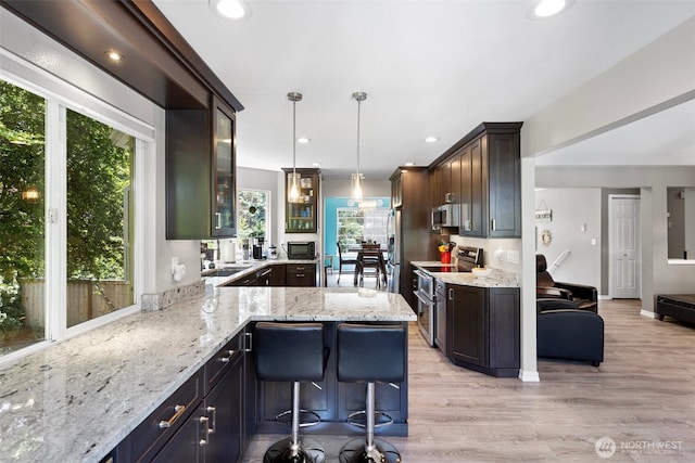 13233 59th Ave W, Edmonds, WA 98026 - kitchen featuring stainless steel appliances, glass insert cabinets, light stone counters, light wood-style floors, and recessed lighting