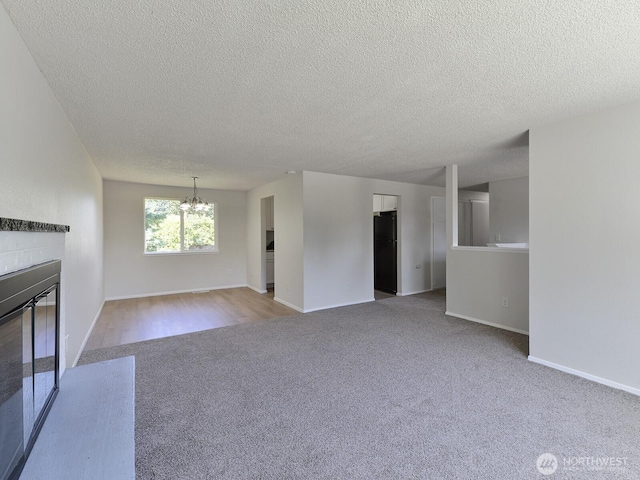 1501 154th St E, Tacoma, WA 98445 - unfurnished living room with carpet flooring, a glass covered fireplace, a chandelier, and a textured ceiling