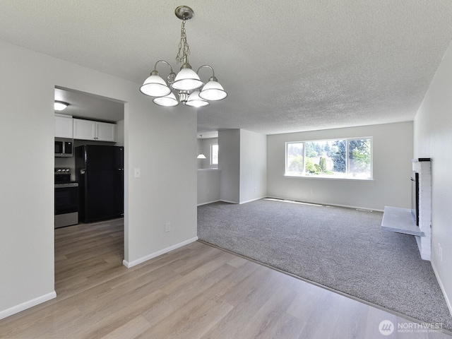 1501 154th St E, Tacoma, WA 98445 - unfurnished dining area with a chandelier, a textured ceiling, and light wood-type flooring
