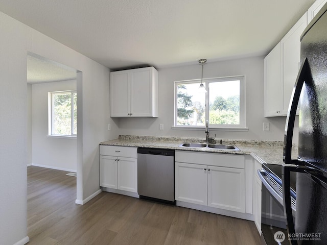1501 154th St E, Tacoma, WA 98445 - kitchen with appliances with stainless steel finishes, light wood finished floors, white cabinets, pendant lighting, and light stone countertops