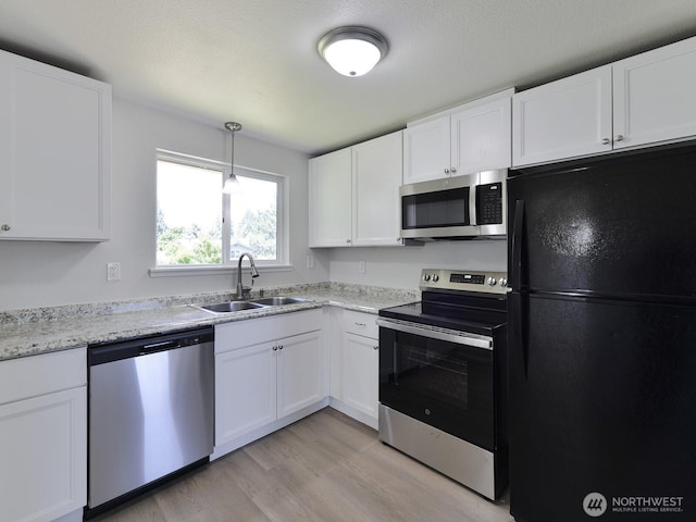 1501 154th St E, Tacoma, WA 98445 - kitchen with stainless steel appliances, white cabinetry, light wood-style flooring, decorative light fixtures, and light stone counters
