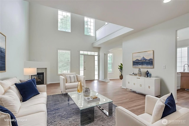 8415 15th Ave SE, Olympia, WA 98513 - living area with a glass covered fireplace, arched walkways, wood finished floors, recessed lighting, and a towering ceiling