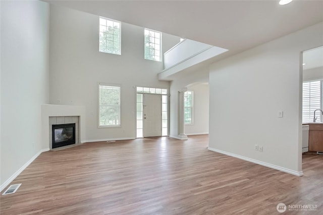 8415 15th Ave SE, Olympia, WA 98513 - unfurnished living room with healthy amount of natural light, a tiled fireplace, wood finished floors, arched walkways, and a high ceiling