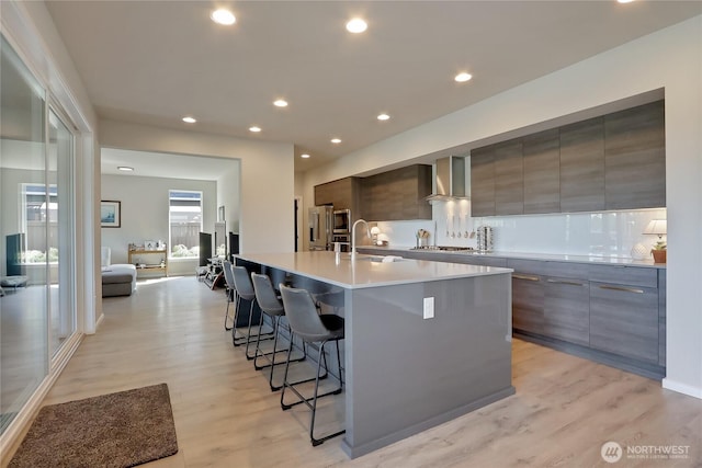 4615 SW Olivine Dr SW, Port Orchard, WA 98367 - kitchen featuring modern cabinets, wall chimney range hood, a breakfast bar area, light wood-style floors, and a large island