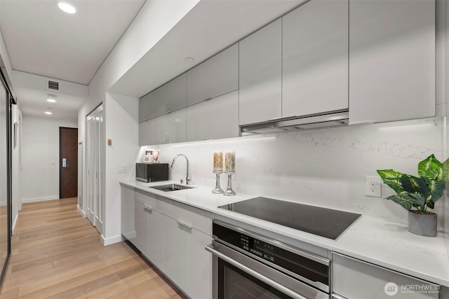 450 S Main St Unit 505, Seattle, WA 98101 - kitchen featuring black appliances, under cabinet range hood, light countertops, light wood-style flooring, and recessed lighting