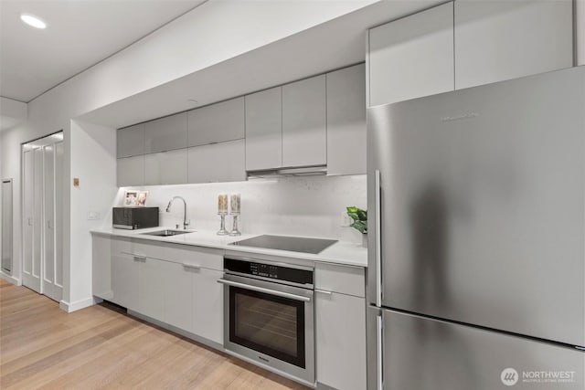 450 S Main St Unit 505, Seattle, WA 98101 - kitchen with stainless steel appliances, light countertops, light wood-type flooring, under cabinet range hood, and modern cabinets