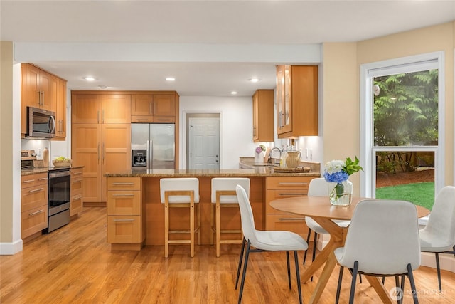 7089 NE Bay Hill Rd, Bainbridge Island, WA 98110 - kitchen with stainless steel appliances, a peninsula, recessed lighting, light stone countertops, and light wood-type flooring