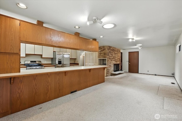 15023 Densmore Ave N, Shoreline, WA 98133 - kitchen featuring stainless steel appliances, a kitchen bar, light carpet, light countertops, and a fireplace