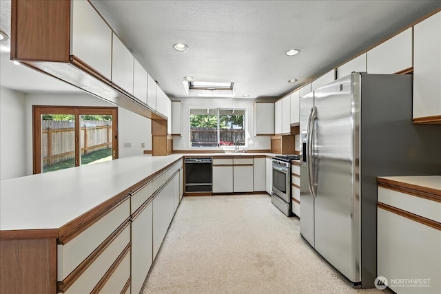 15023 Densmore Ave N, Shoreline, WA 98133 - kitchen featuring stainless steel appliances, a peninsula, white cabinets, light carpet, and recessed lighting