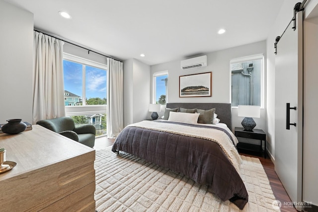 4119 Wallingford Ave N Unit C, Seattle, WA 98103 - bedroom featuring a barn door, a wall mounted AC, wood finished floors, and recessed lighting
