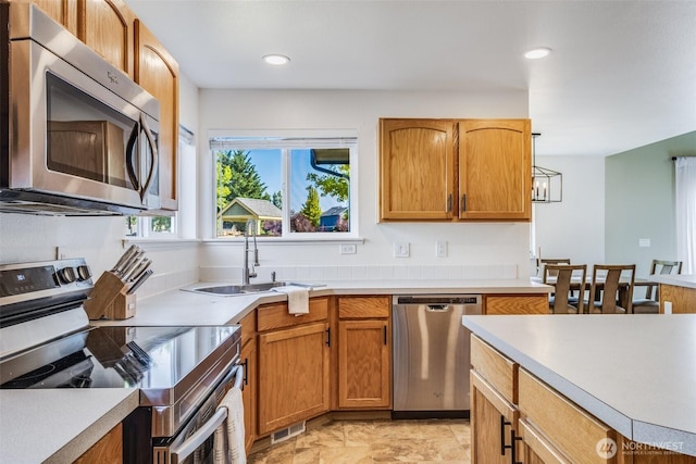 6713 135th E, Puyallup, WA 98373 - kitchen featuring appliances with stainless steel finishes, light countertops, recessed lighting, and brown cabinetry