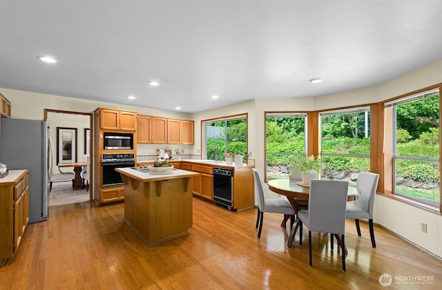 16909 NE 37th Pl, Bellevue, WA 98008 - kitchen with black appliances, light countertops, a kitchen island, light wood-type flooring, and recessed lighting