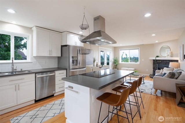 3918 Commencement Bay Dr, Tacoma, WA 98407 - kitchen with appliances with stainless steel finishes, island range hood, dark countertops, open floor plan, and white cabinets