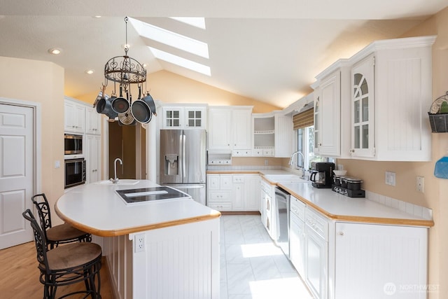 350 E Division Ave, Ephrata, WA 98823 - kitchen with appliances with stainless steel finishes, a skylight, vaulted ceiling, an island with sink, and a kitchen bar
