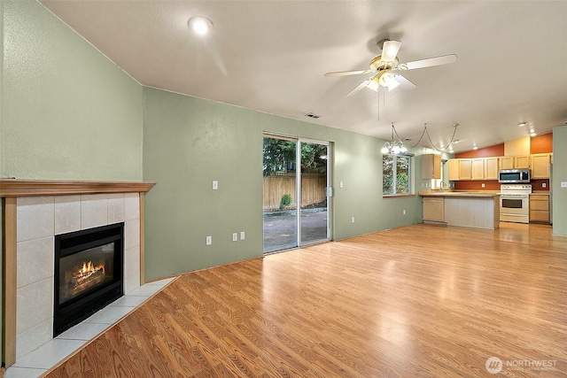 3117 243rd Street Ct E, Spanaway, WA 98387 - unfurnished living room with light wood-type flooring, lofted ceiling, a tiled fireplace, and a ceiling fan