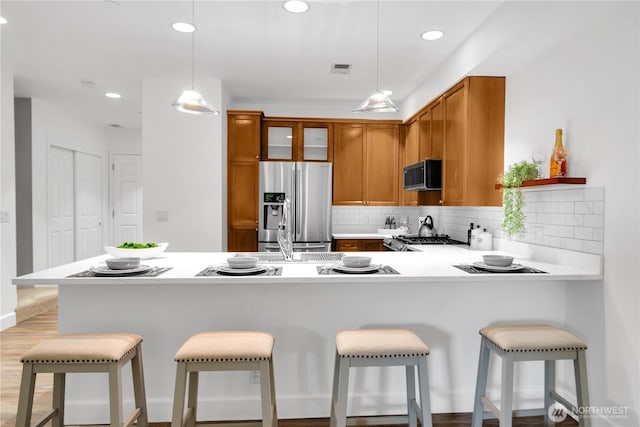 7549 SE 29th St Unit 301, Mercer Island, WA 98040 - kitchen with appliances with stainless steel finishes, brown cabinetry, tasteful backsplash, light countertops, and recessed lighting