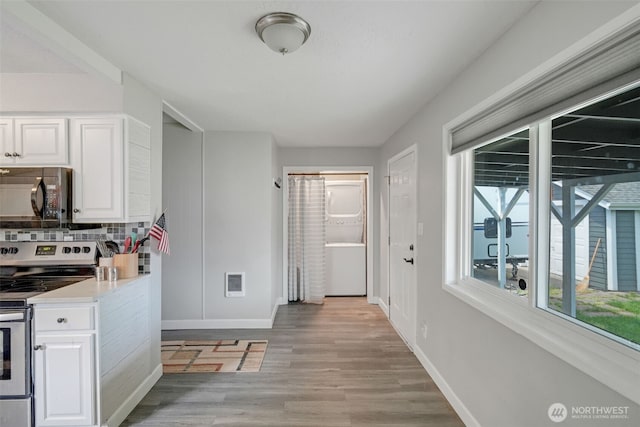 467 22nd Ave, Longview, WA 98632 - kitchen with black microwave, stainless steel range with electric cooktop, light wood-style floors, tasteful backsplash, and white cabinets