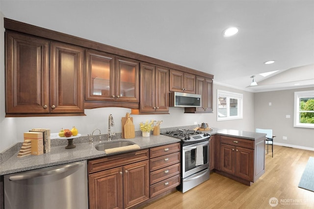 8410 9th Ave SW, Seattle, WA 98106 - kitchen featuring stainless steel appliances, a peninsula, light wood-style flooring, light stone countertops, and recessed lighting