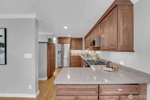 8410 9th Ave SW, Seattle, WA 98106 - kitchen with stainless steel appliances, crown molding, light stone counters, light wood-style flooring, and brown cabinets