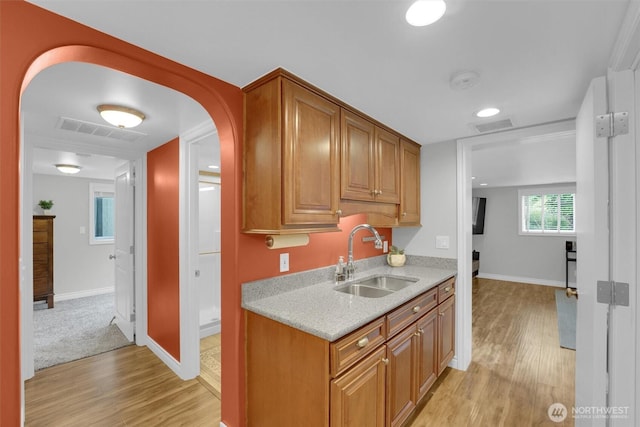 8410 9th Ave SW, Seattle, WA 98106 - kitchen with light wood-type flooring, light stone counters, brown cabinetry, and arched walkways