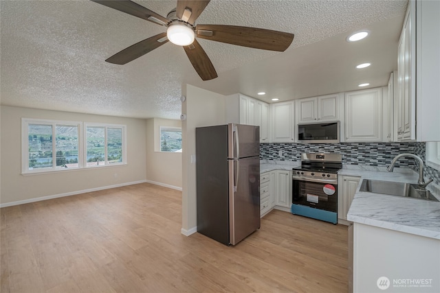 2117 S Majestic Dr, East Wenatchee, WA 98802 - kitchen featuring stainless steel appliances, a textured ceiling, light countertops, light wood-type flooring, and tasteful backsplash