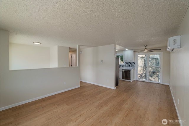 2117 S Majestic Dr, East Wenatchee, WA 98802 - unfurnished living room featuring an AC wall unit, light wood-type flooring, a textured ceiling, and ceiling fan