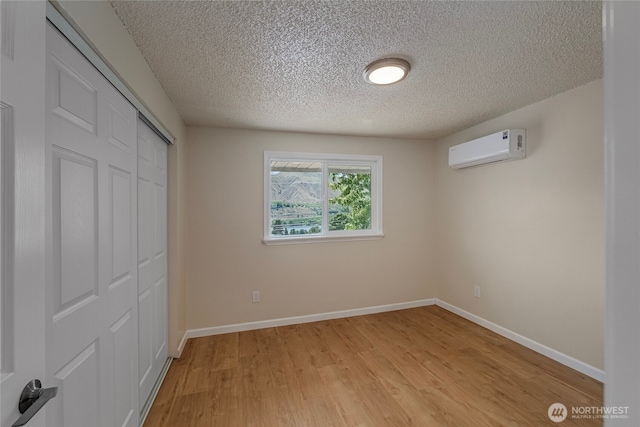 2117 S Majestic Dr, East Wenatchee, WA 98802 - unfurnished bedroom featuring a wall mounted air conditioner, a textured ceiling, a closet, and light wood finished floors