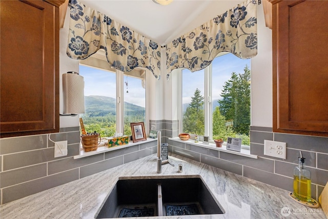 22655 Nature View Dr, Sedro Woolley, WA 98284 - kitchen featuring decorative backsplash, plenty of natural light, light stone countertops, vaulted ceiling, and brown cabinetry