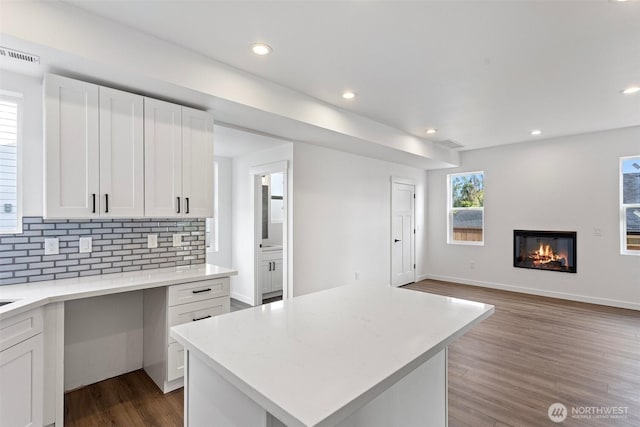 7812 S Sheridan Ave, Tacoma, WA 98408 - kitchen featuring a glass covered fireplace, wood finished floors, light countertops, backsplash, and white cabinets