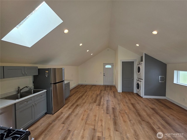 410 Eddy Ct, Port Townsend, WA 98368 - kitchen featuring stacked washer / dryer, freestanding refrigerator, a skylight, gray cabinets, and vaulted ceiling