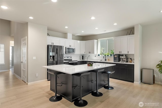 16712 8th Ave E, Spanaway, WA 98387 - kitchen featuring stainless steel appliances, light wood-style floors, backsplash, a kitchen breakfast bar, and recessed lighting