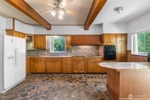 6928 View Park Rd SE, Port Orchard, WA 98367 - kitchen with white fridge with ice dispenser, black oven, stone floors, beamed ceiling, and brown cabinets