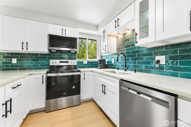 60 E Olyview Pl, Grapeview, WA 98546 - kitchen with appliances with stainless steel finishes, white cabinetry, glass insert cabinets, and decorative backsplash