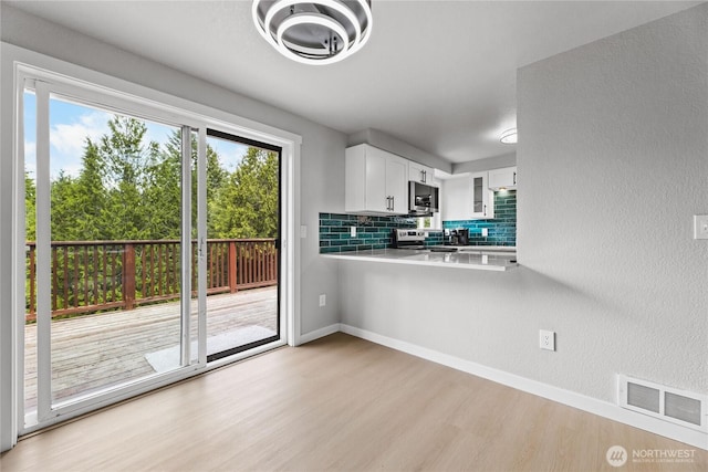 60 E Olyview Pl, Grapeview, WA 98546 - kitchen with appliances with stainless steel finishes, light wood-style floors, light countertops, white cabinetry, and tasteful backsplash