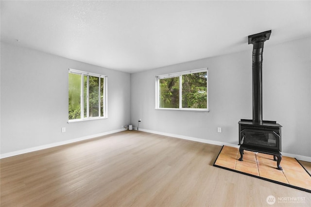 60 E Olyview Pl, Grapeview, WA 98546 - unfurnished living room featuring a wood stove, healthy amount of natural light, and wood finished floors